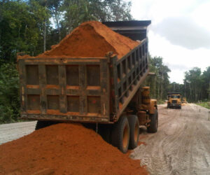 dump truck laying red dirt down